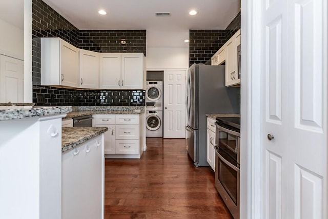 1732 Peachtree Path Unit 4, Stevensville, MI 49127 - kitchen featuring stacked washer and clothes dryer, range with two ovens, light stone countertops, white cabinetry, and dark wood-type flooring