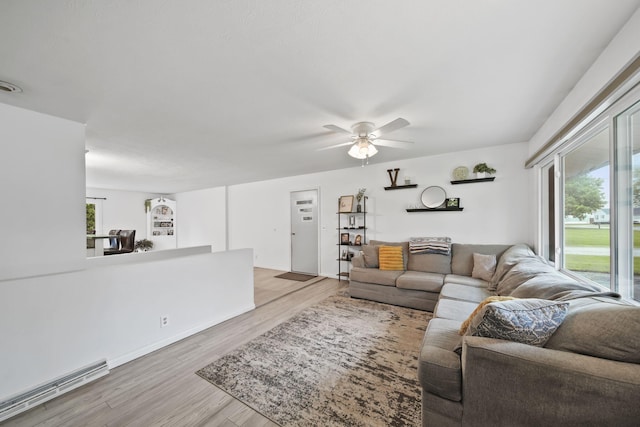 2837 Elmwood Dr, Adrian, MI 49221 - living room featuring a baseboard heating unit, plenty of natural light, a ceiling fan, and light wood-style floors