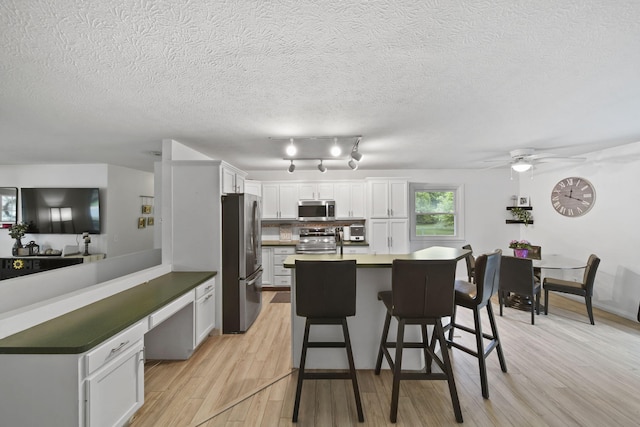 2837 Elmwood Dr, Adrian, MI 49221 - kitchen featuring stainless steel appliances, a peninsula, a breakfast bar area, light wood-style flooring, and a ceiling fan