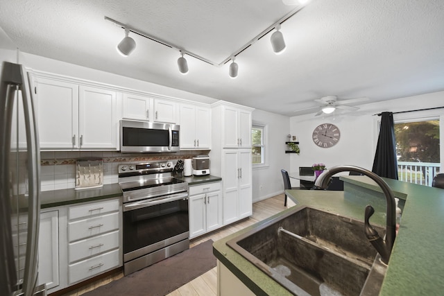 2837 Elmwood Dr, Adrian, MI 49221 - kitchen with appliances with stainless steel finishes, a sink, decorative backsplash, light wood-style floors, and a textured ceiling