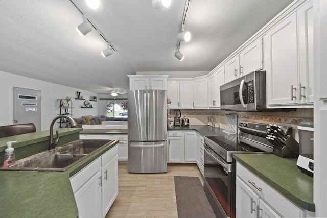 2837 Elmwood Dr, Adrian, MI 49221 - kitchen featuring appliances with stainless steel finishes, a sink, light wood-style floors, white cabinets, and dark countertops