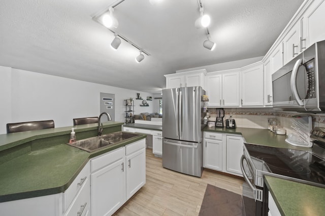 2837 Elmwood Dr, Adrian, MI 49221 - kitchen with appliances with stainless steel finishes, a sink, dark countertops, light wood-style floors, and white cabinetry