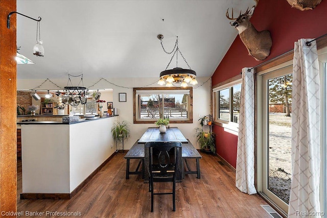 5240 Thomas Rd, Metamora, MI 48455 - dining area featuring wood finished floors, baseboards, vaulted ceiling, and a chandelier
