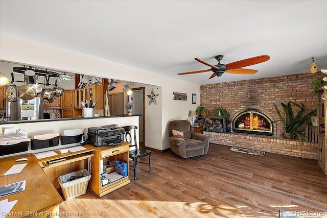5240 Thomas Rd, Metamora, MI 48455 - living room featuring ceiling fan, brick wall, a fireplace, and wood finished floors
