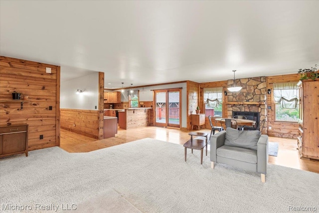 3434 Brown City Rd, Imlay City, MI 48444 - living area with wooden walls, a stone fireplace, wainscoting, light carpet, and light wood-type flooring
