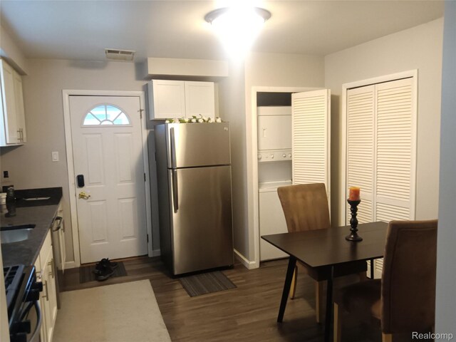 3246 Harris St, Ferndale, MI 48220 - kitchen with freestanding refrigerator, stacked washing machine and dryer, range with gas cooktop, white cabinetry, and dark wood-style floors