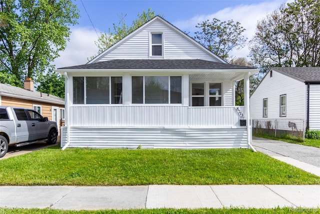 8713 Hupp Ave, Warren, MI 48089 - view of front of house with a front yard, covered porch, a sunroom, and a shingled roof