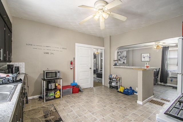 2149 Luella St, Kalamazoo, MI 49001 - kitchen featuring ceiling fan, stainless steel microwave, light countertops, arched walkways, and baseboards