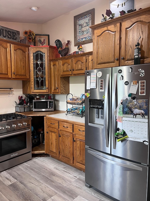 132 W Lansing Rd, Morrice, MI 48857 - kitchen featuring stainless steel appliances, light countertops, light wood-type flooring, and brown cabinets