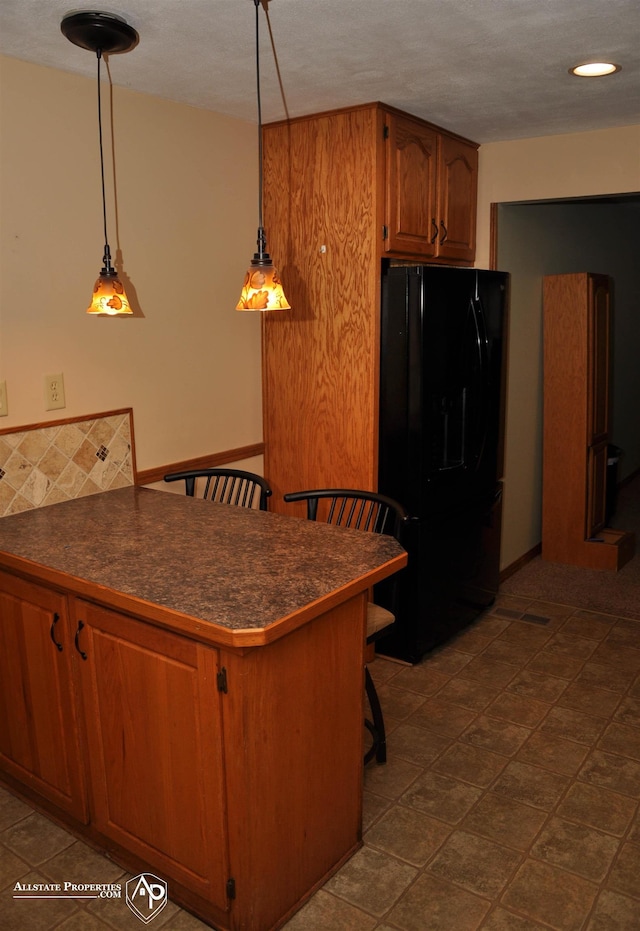 3478 N Gale Rd, Davison, MI 48423 - kitchen featuring freestanding refrigerator, dark countertops, a peninsula, a kitchen bar, and brown cabinetry