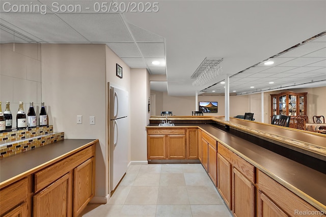 16106 Nathan Dr, Macomb, MI 48044 - kitchen featuring freestanding refrigerator, tasteful backsplash, brown cabinets, a paneled ceiling, and a sink