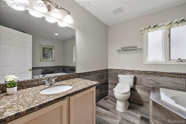 16106 Nathan Dr, Macomb, MI 48044 - bathroom featuring tile walls, a garden tub, toilet, vanity, and a wainscoted wall