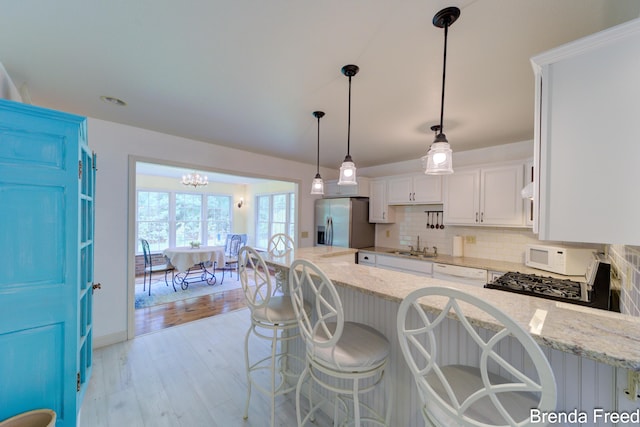 7561 Wiczer Dr, Whitehall, MI 49461 - kitchen featuring white appliances, a sink, decorative backsplash, white cabinets, and light wood-style floors