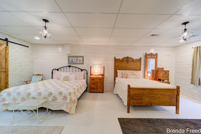 7561 Wiczer Dr, Whitehall, MI 49461 - bedroom with a barn door, a drop ceiling, tile patterned floors, wooden walls, and a chandelier