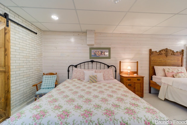 7561 Wiczer Dr, Whitehall, MI 49461 - bedroom featuring a drop ceiling, a barn door, concrete floors, and wooden walls