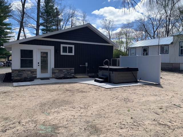 855 W Locust St, White Cloud, MI 49349 - rear view of property with a hot tub, cooling unit, and stone siding