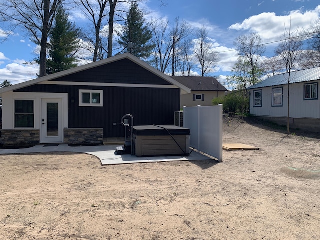855 W Locust St, White Cloud, MI 49349 - rear view of house featuring central air condition unit, a patio area, stone siding, and a hot tub