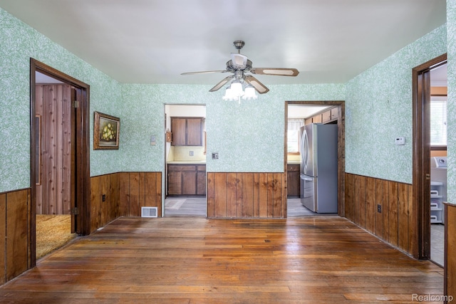 2500 Howe St, Shelby, MI 48317 - unfurnished living room featuring a wainscoted wall, hardwood / wood-style floors, a ceiling fan, healthy amount of natural light, and wood walls