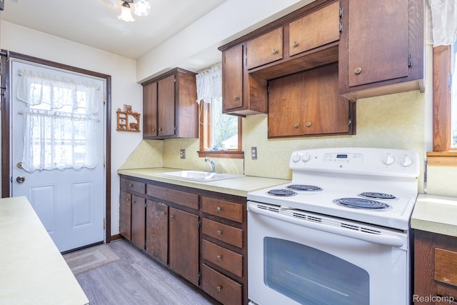 2500 Howe St, Shelby, MI 48317 - kitchen featuring white range with electric stovetop, a sink, light countertops, and light wood-style floors