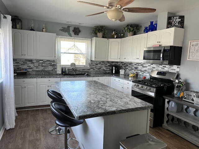 406 S Elm Ave, Jackson, MI 49203 - kitchen with stainless steel appliances, ceiling fan, dark wood-type flooring, tasteful backsplash, and a breakfast bar area