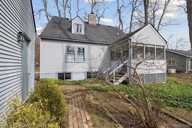 2095 E Nalone, Wixom, MI 48393 - back of property with a chimney, a sunroom, and a shingled roof