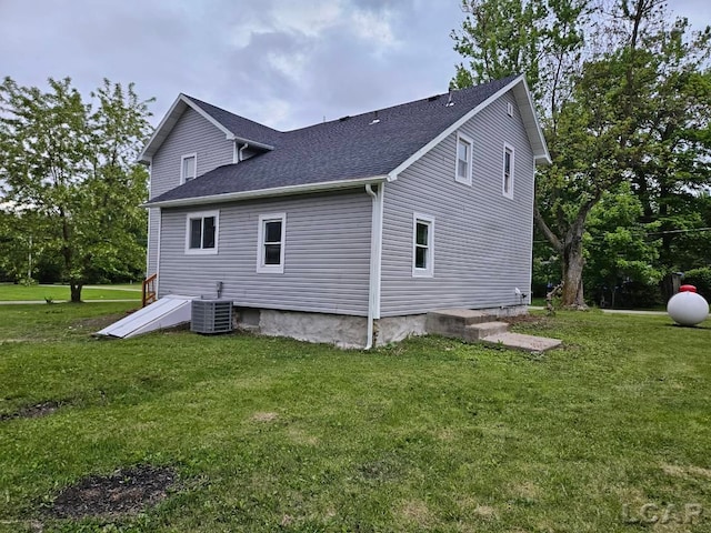 17045 Mill St, Hudson, MI 49247 - back of house featuring roof with shingles, a lawn, and central AC unit