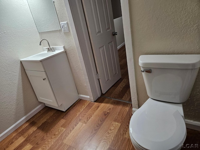 17045 Mill St, Hudson, MI 49247 - half bathroom with a textured wall, toilet, vanity, wood finished floors, and baseboards