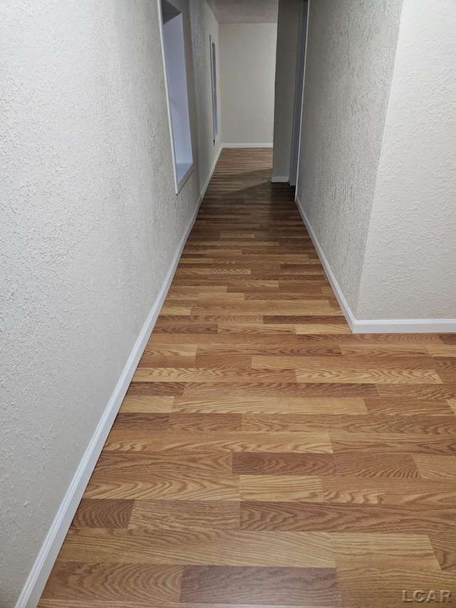 17045 Mill St, Hudson, MI 49247 - hall featuring wood finished floors, a textured wall, and baseboards