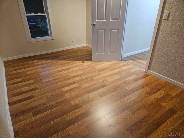 17045 Mill St, Hudson, MI 49247 - unfurnished bedroom with wood finished floors, a textured wall, and baseboards