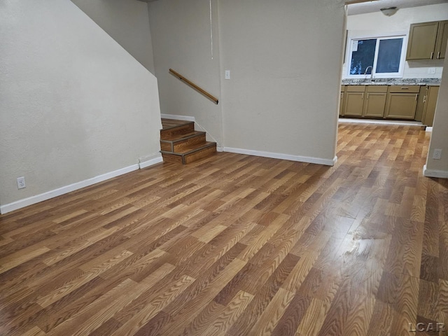 17045 Mill St, Hudson, MI 49247 - unfurnished living room featuring a sink, light wood-type flooring, baseboards, and stairway
