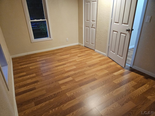 17045 Mill St, Hudson, MI 49247 - unfurnished bedroom with light wood-style floors, baseboards, and a textured wall