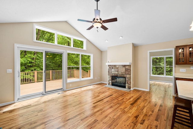 64711 Shorewood Ln, Cassopolis, MI 49031 - unfurnished living room with high vaulted ceiling, a ceiling fan, light wood-style flooring, a fireplace, and baseboards