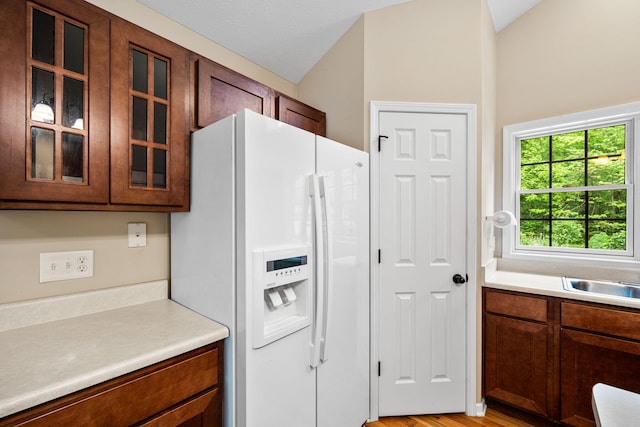 64711 Shorewood Ln, Cassopolis, MI 49031 - kitchen with white refrigerator with ice dispenser, glass insert cabinets, lofted ceiling, light countertops, and light wood-style flooring