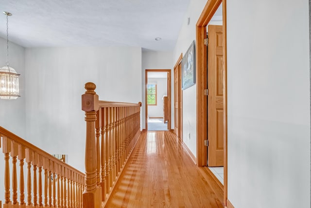 6248 Black Forest Trl, Muskegon, MI 49442 - hallway featuring an upstairs landing, a chandelier, light wood-type flooring, and baseboards