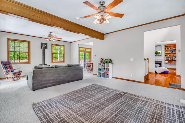 6248 Black Forest Trl, Muskegon, MI 49442 - carpeted living room featuring a ceiling fan, a wood stove, baseboards, ornamental molding, and beamed ceiling