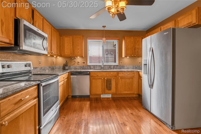 19298 Mitchell St, Rockwood, MI 48173 - kitchen with stainless steel appliances, a ceiling fan, light wood-style floors, a sink, and brown cabinetry