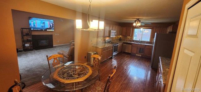 19298 Mitchell St, Rockwood, MI 48173 - kitchen with stainless steel appliances, a glass covered fireplace, a sink, dark wood-type flooring, and stone counters