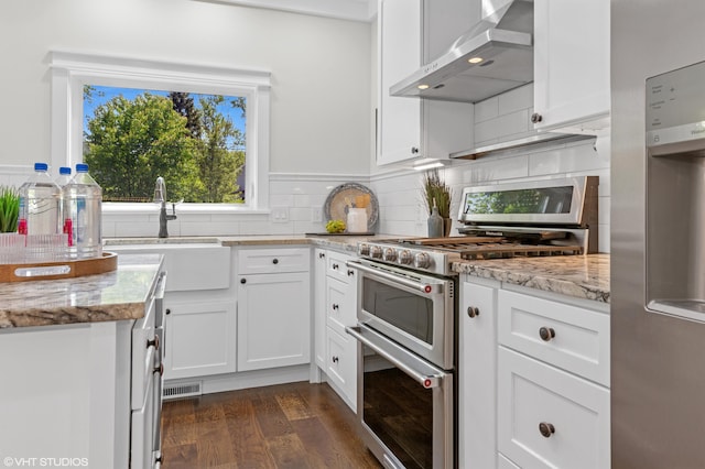 1310 Harrison Ave, Saint Joseph, MI 49085 - kitchen featuring wall chimney range hood, appliances with stainless steel finishes, a sink, and white cabinetry