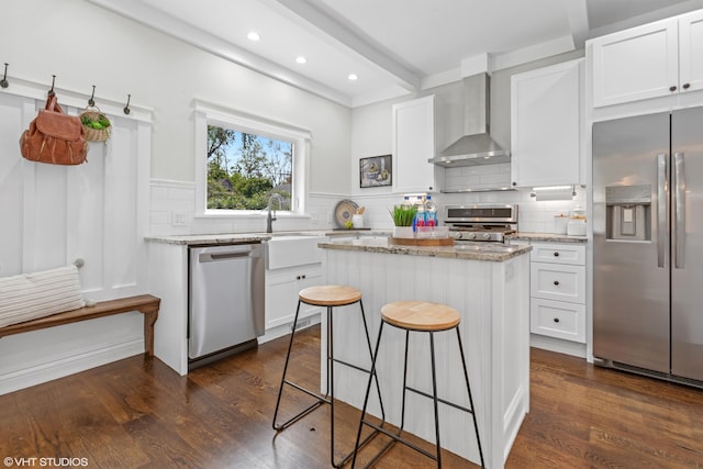 1310 Harrison Ave, Saint Joseph, MI 49085 - kitchen with appliances with stainless steel finishes, wall chimney exhaust hood, dark wood-type flooring, a kitchen island, and white cabinetry