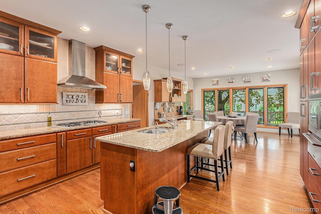3870 Glen Falls Dr, Bloomfield Hills, MI 48302 - kitchen with wall chimney exhaust hood, a sink, stainless steel gas cooktop, brown cabinets, and light wood finished floors