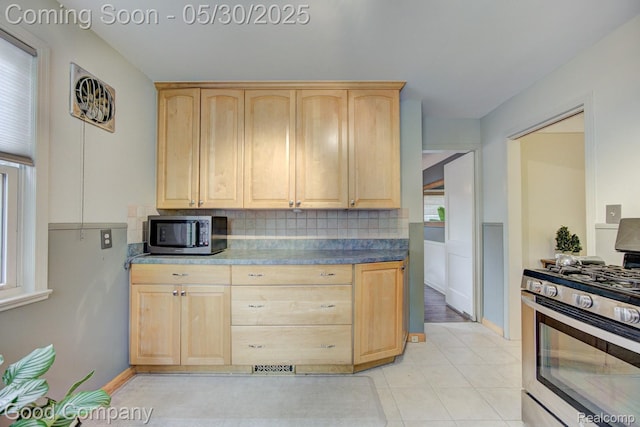 1012 W 12 Mile Rd, Royal Oak, MI 48073 - kitchen with light brown cabinetry, stainless steel appliances, backsplash, light tile patterned floors, and baseboards