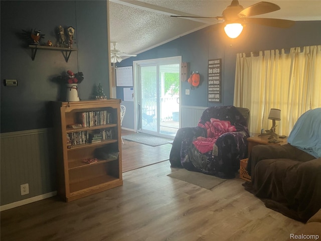 402 Katie Ln, Morrice, MI 48857 - living area with a ceiling fan, vaulted ceiling, a textured ceiling, a wainscoted wall, and wood finished floors