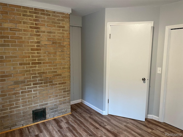 478 Karcher Rd, Rose City, MI 48654 - unfurnished bedroom with baseboards, wood finished floors, and brick wall
