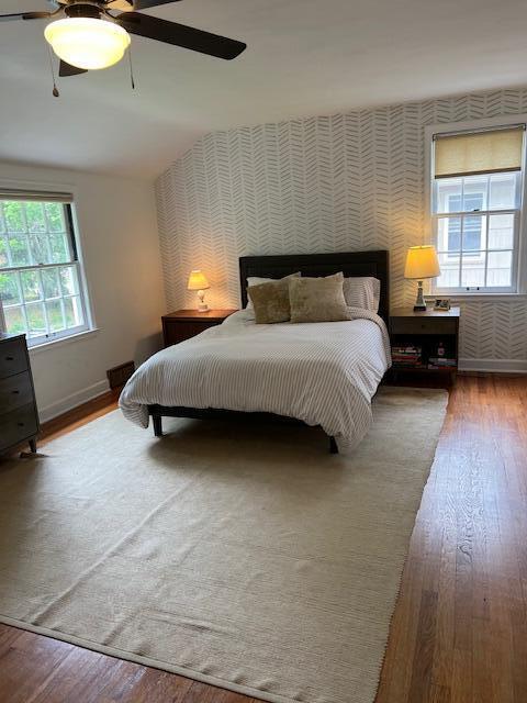 808 Princeton Ave, Ann Arbor, MI 48103 - bedroom with wallpapered walls, hardwood / wood-style floors, an accent wall, ceiling fan, and baseboards
