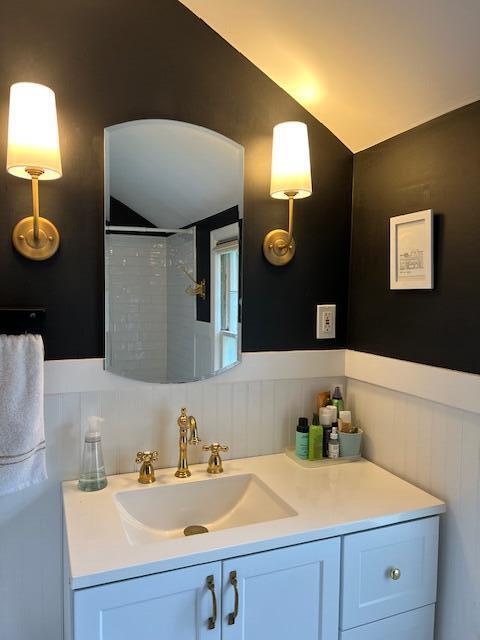 808 Princeton Ave, Ann Arbor, MI 48103 - bathroom featuring lofted ceiling, vanity, a wainscoted wall, and a shower