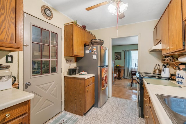 75 Taylor Ave, Battle Creek, MI 49037 - kitchen with under cabinet range hood, freestanding refrigerator, brown cabinetry, range with electric cooktop, and a ceiling fan