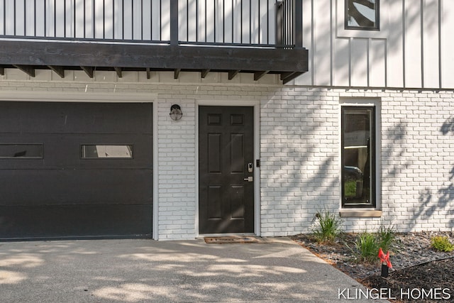 127 Emmet St, Grand Haven, MI 49417 - property entrance with a garage, brick siding, board and batten siding, and a balcony
