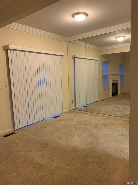 1240 University Dr Unit 2, Pontiac, MI 48342 - empty room featuring crown molding, carpet, baseboards, and a fireplace