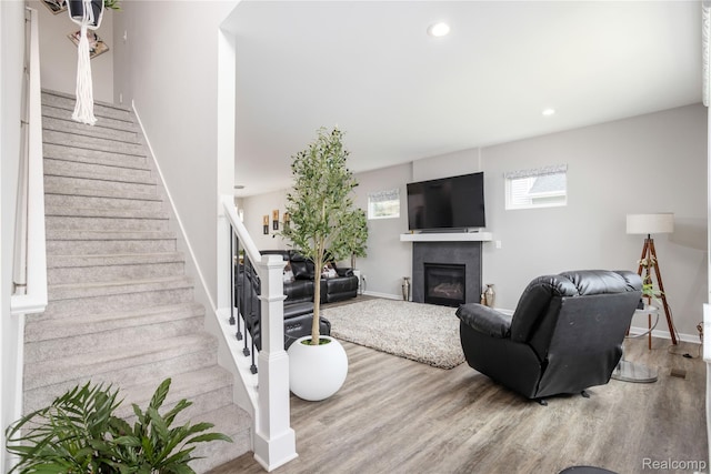 132 Copper Ridge Ct, Walled Lake, MI 48390 - living area with stairway, wood finished floors, healthy amount of natural light, a glass covered fireplace, and recessed lighting