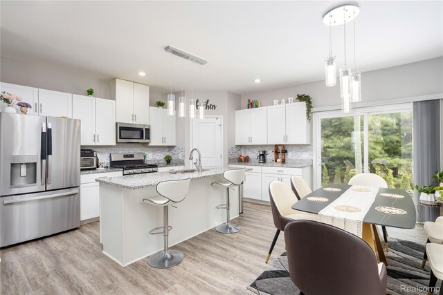132 Copper Ridge Ct, Walled Lake, MI 48390 - kitchen with stainless steel appliances, a sink, decorative backsplash, white cabinets, and a breakfast bar
